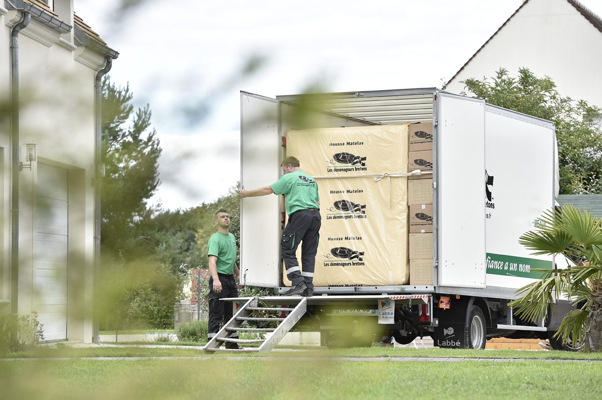 Camion de d&eacute;m&eacute;nagement Les d&eacute;m&eacute;nageurs bretons stationn&eacute; devant une maison, hayon &agrave; l&rsquo;arri&egrave;re